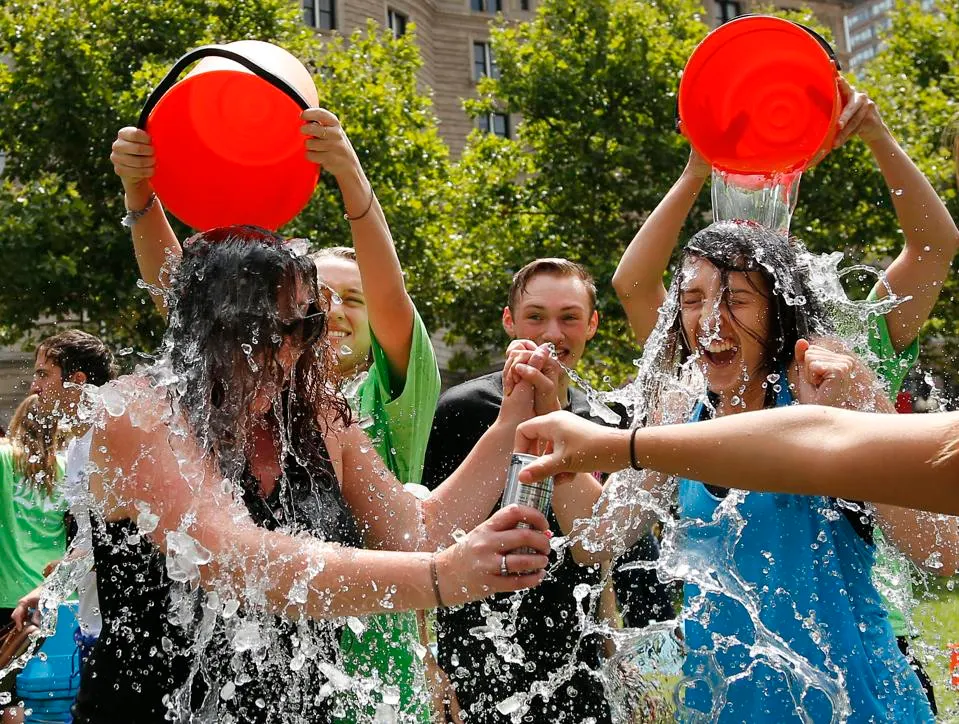 FILE - In this Aug. 7, 2014, file photo, two women get doused during the ice bucket challenge at Boston's Copley Square to raise funds and awareness for ALS. The ALS Association says money raised through the challenge helped fund a project that has discovered a gene linked to the disease. (AP Photo/Elise Amendola, File) ASSOCIATED PRESS