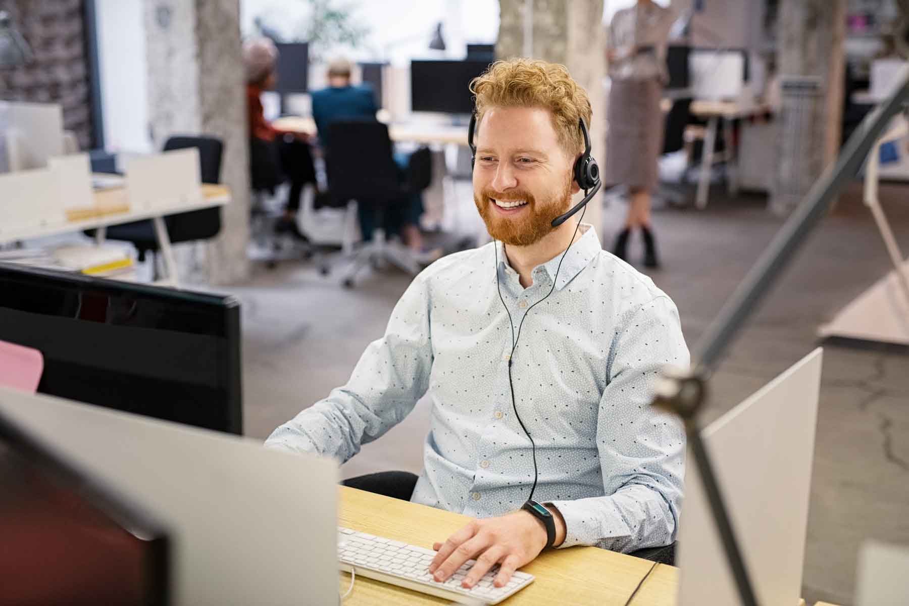 Hero image of a man talking on a headset in an office